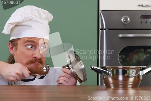 Image of Funny young chef strange looking at pot