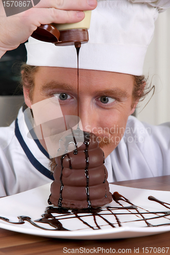 Image of Funny young chef added chocolate sauce at piece of cake