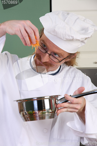 Image of Funny young chef add carrots in the pot