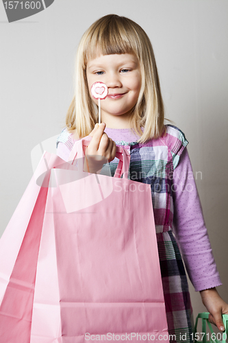 Image of Little girl with shopping bags and lollipop