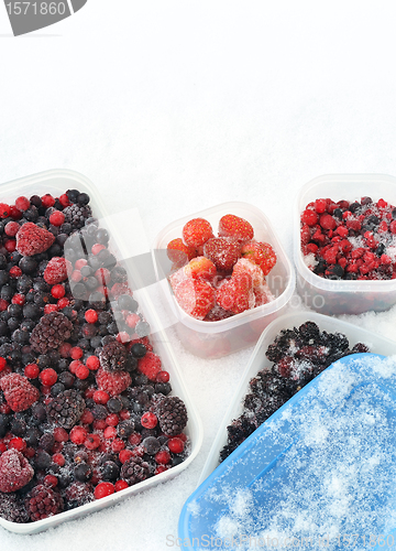 Image of Plastic containers of frozen mixed berries in snow 