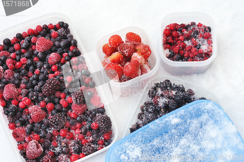 Image of Plastic containers of frozen mixed berries in snow