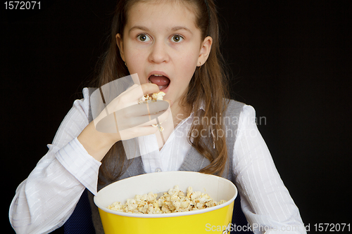 Image of surprised girl with popcorn on a black background