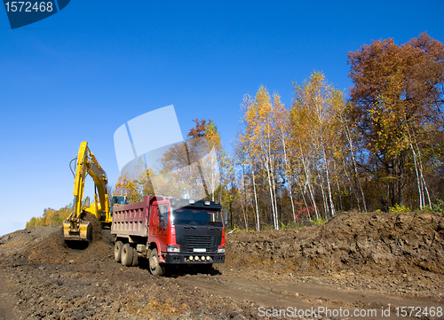 Image of Yellow backhoe and truck.