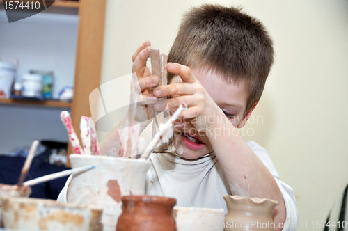 Image of child  boy shaping clay in pottery studio