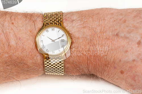 Image of Gold watch with white face on hairy wrist