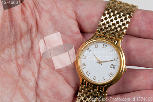 Image of Gold watch with white face in palm of hand