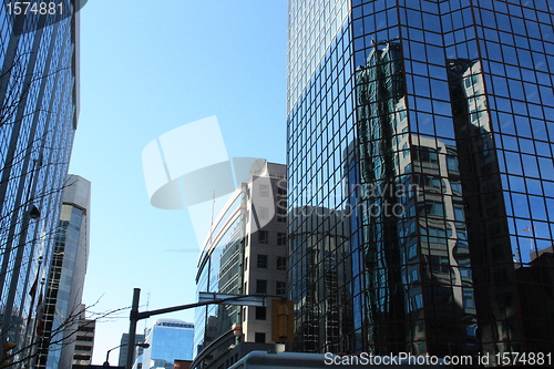 Image of Buildings,flag and clear sky reflected on blue glass of a building, Queen St. 