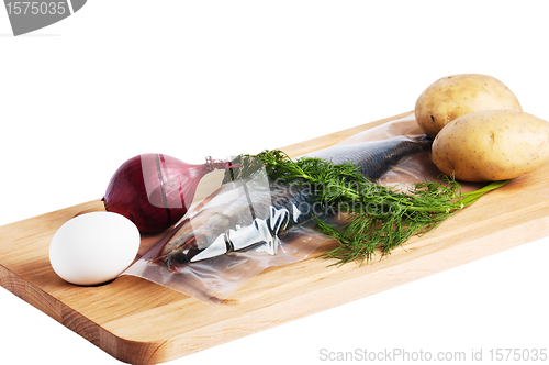 Image of Vegetables and a salty herring on a kitchen board