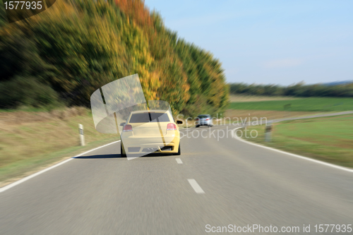 Image of silver and yellow car driving on the road