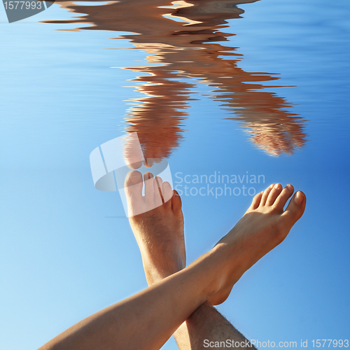 Image of human legs on the blue water in summer