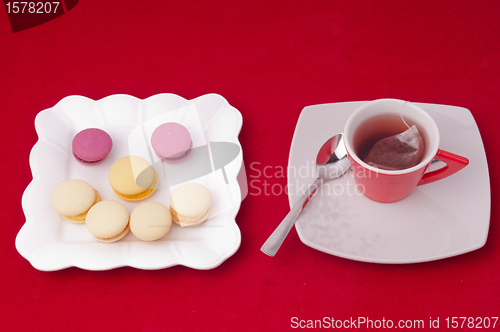 Image of Cup of tea and smile of macaroons on velvet tablecloth