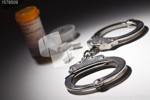 Image of Handcuffs, Medicine Bottle and Pills Under Spot Light