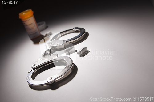 Image of Handcuffs, Medicine Bottle and Pills Under Spot Light