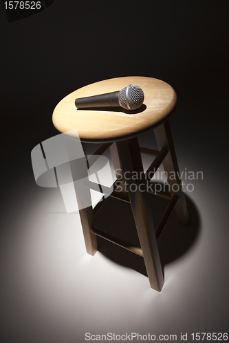 Image of Microphone Laying on Wooden Stool Under Spotlight