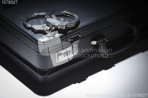 Image of Pair of Handcuffs and Briefcase Under Spot Light