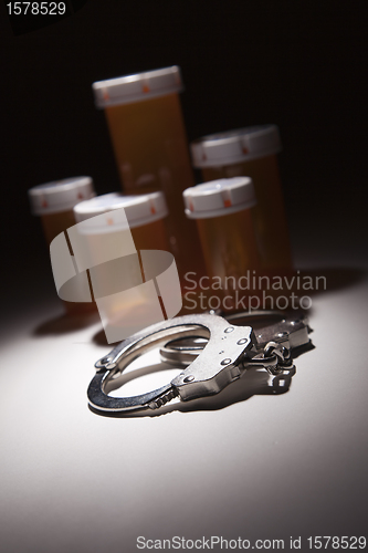 Image of Handcuffs, Medicine Bottle and Pills Under Spot Light