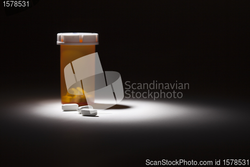 Image of Medicine Bottle and Pills Under Spot Light