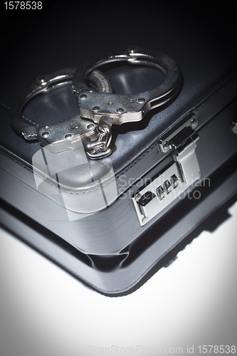 Image of Pair of Handcuffs and Briefcase Under Spot Light