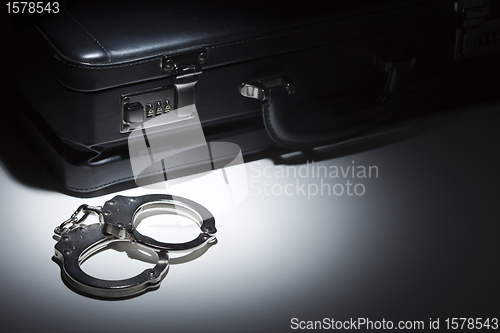 Image of Pair of Handcuffs and Briefcase Under Spot Light