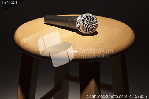 Image of Microphone Laying on Wooden Stool Under Spotlight