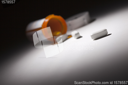 Image of Medicine Bottle and Pills Under Spot Light