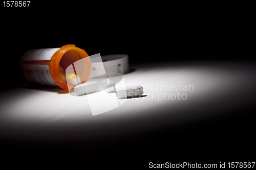 Image of Medicine Bottle and Pills Under Spot Light