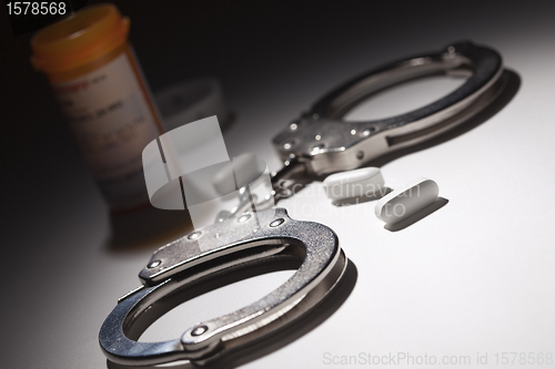 Image of Handcuffs, Medicine Bottle and Pills Under Spot Light