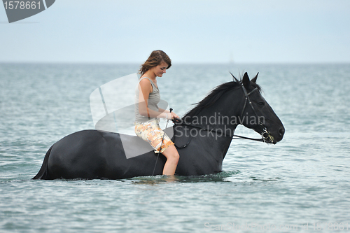 Image of woman and  horse in the sea