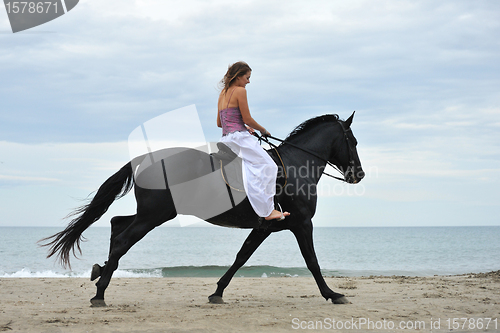 Image of woman and  horse on the beach