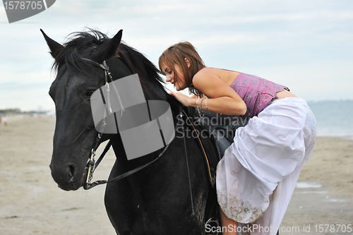 Image of woman mount a  horse on the beach