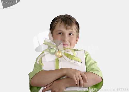 Image of Child holding a wrapped present and thoughtfully looking up