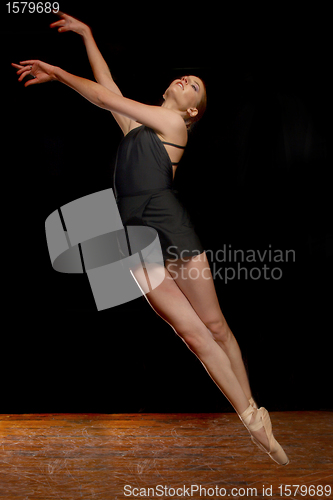 Image of Beautiful Ballerina Leaping in Studio on Black Background