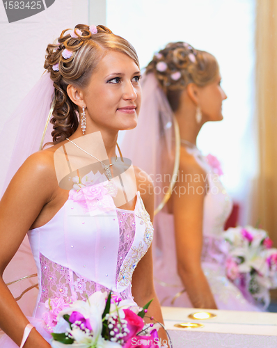 Image of Beautiful bride in a pink dress near the mirror