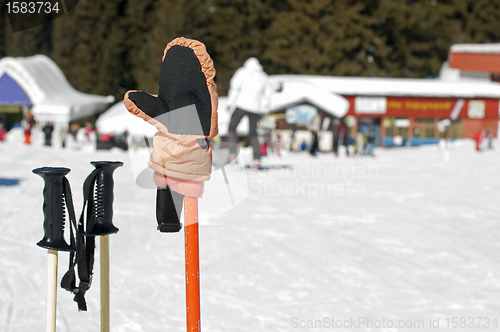 Image of Ski gloves and sticks. Winter tourists on the background