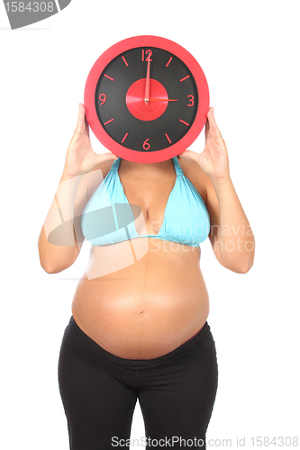 Image of beautiful pregnant woman holding clock in hands