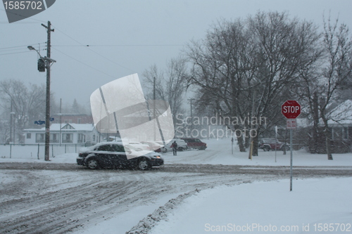 Image of Picture taken during a winter storm that passed by the city - snow covered a busy intersection - car passing