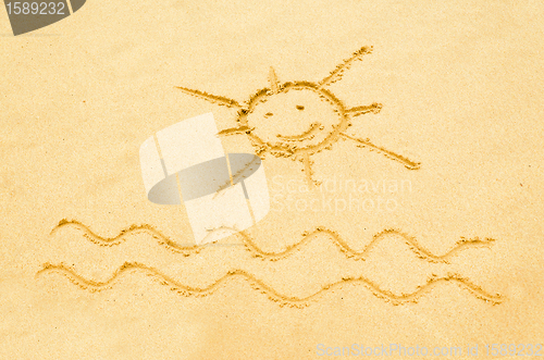 Image of Smiling sun drawn on a sandy beach