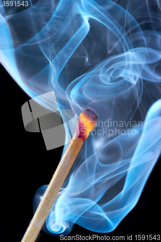 Image of Photo of a burning match in a smoke on a black background 