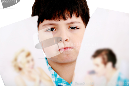 Image of Upset boy standing in front pcture of parents with problems agai