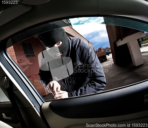 Image of robber and the thief in a mask hijacks the car