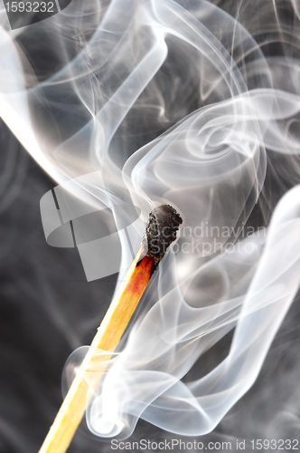 Image of Photo of a burning match in a smoke on a black background