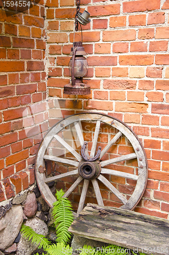 Image of Antique wooden carriage wheel and kerosine lamp  