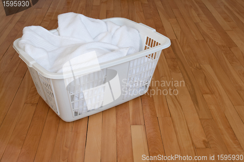 Image of Laundry basket with white towels on wooden floor