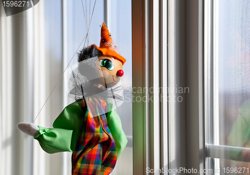 Image of String puppet gazing outside window in sun