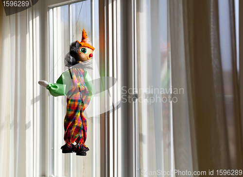 Image of String puppet gazing outside window in sun