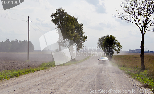 Image of Dusty rural gravel road between farm fields 