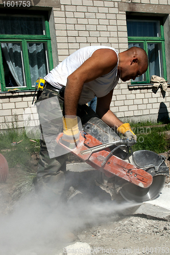 Image of Worker with industrial saw cutting a concrete block