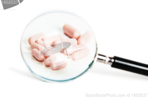 Image of Group of different pills on magnifying glass. On white backgroun