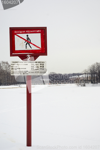 Image of Frozen lake in winter and warning sign